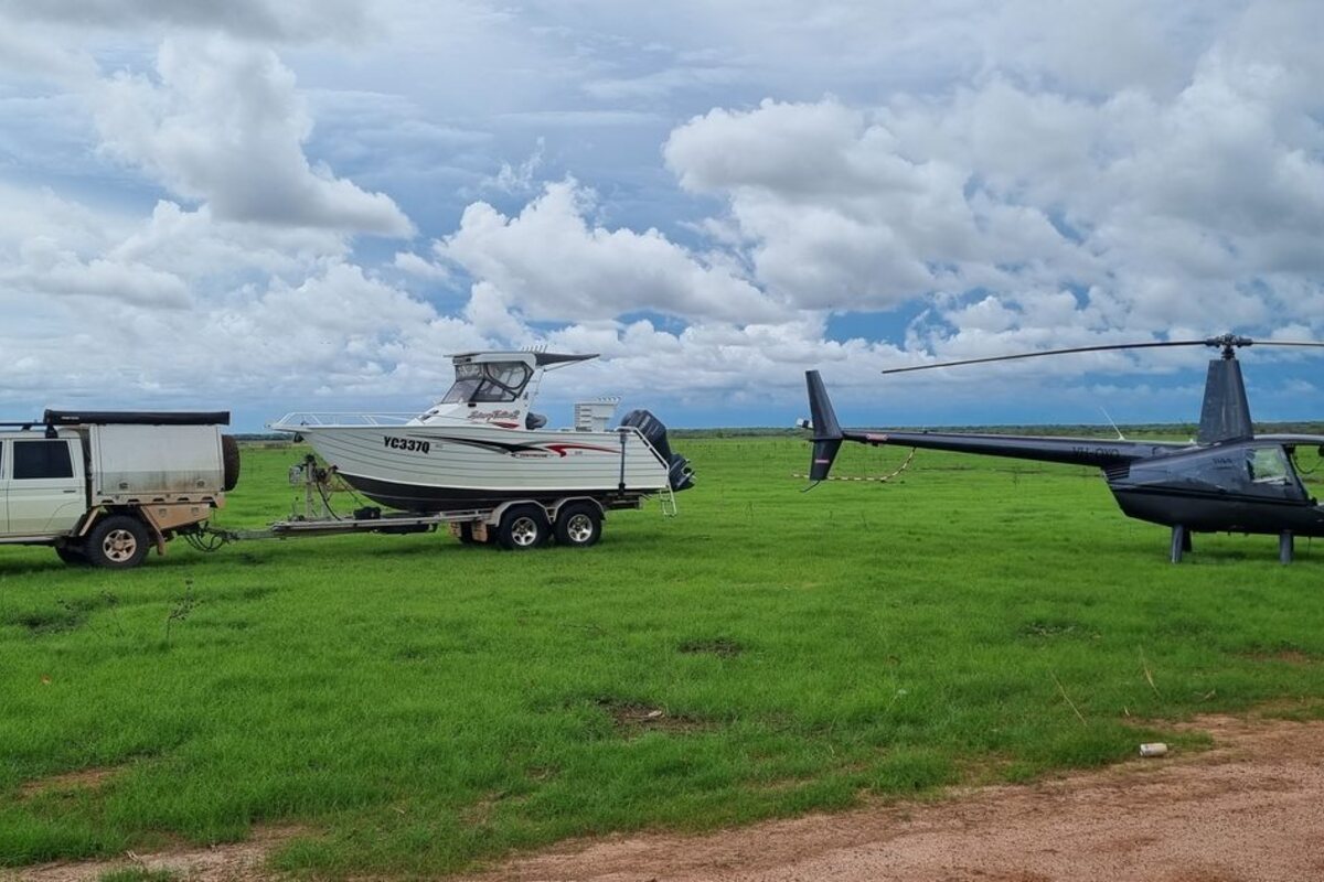 Helicopter beside a boat and 4WD, ready to ferry gear to a remote fishing spot